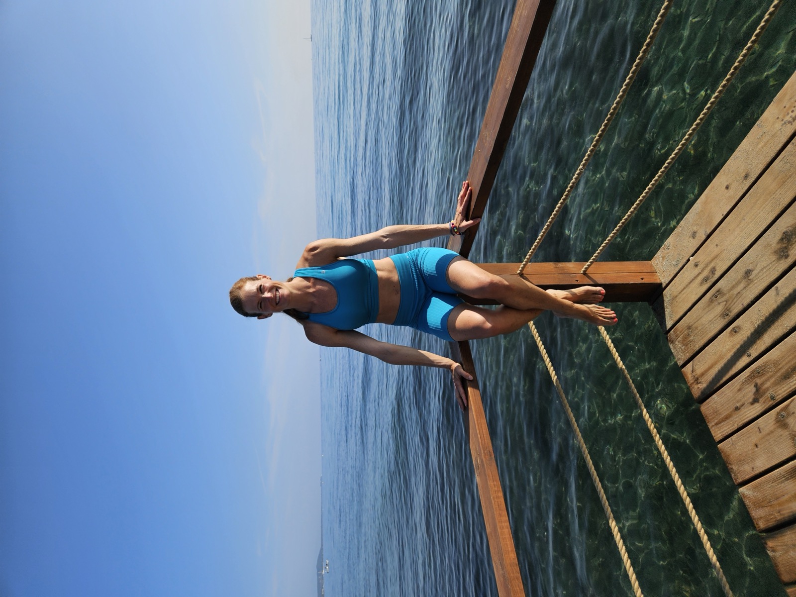 Katja sitzt am Wasser auf einem Holzsteg